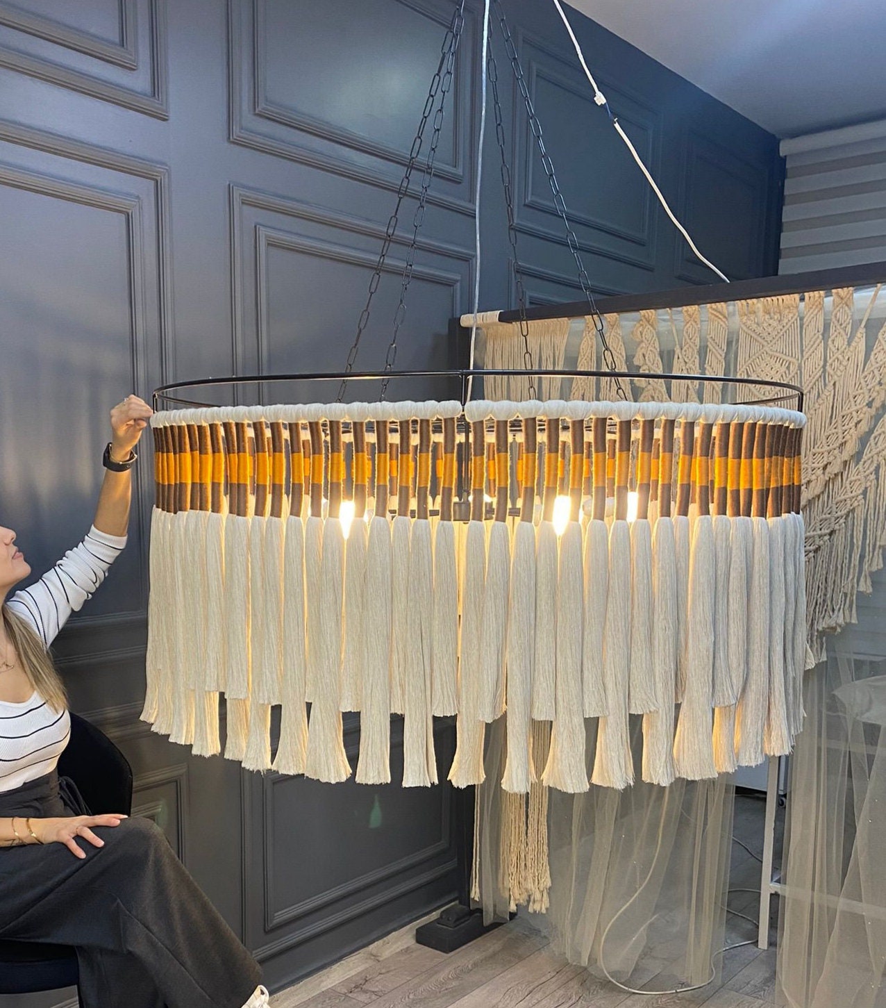 A large handmade chandelier featuring a modern boho style with tassels made fram natural cotton details. this oversized statement lighting piece is ideal for high ceilings and adds a luxurious, rustic touch to any space, blending natural materal.