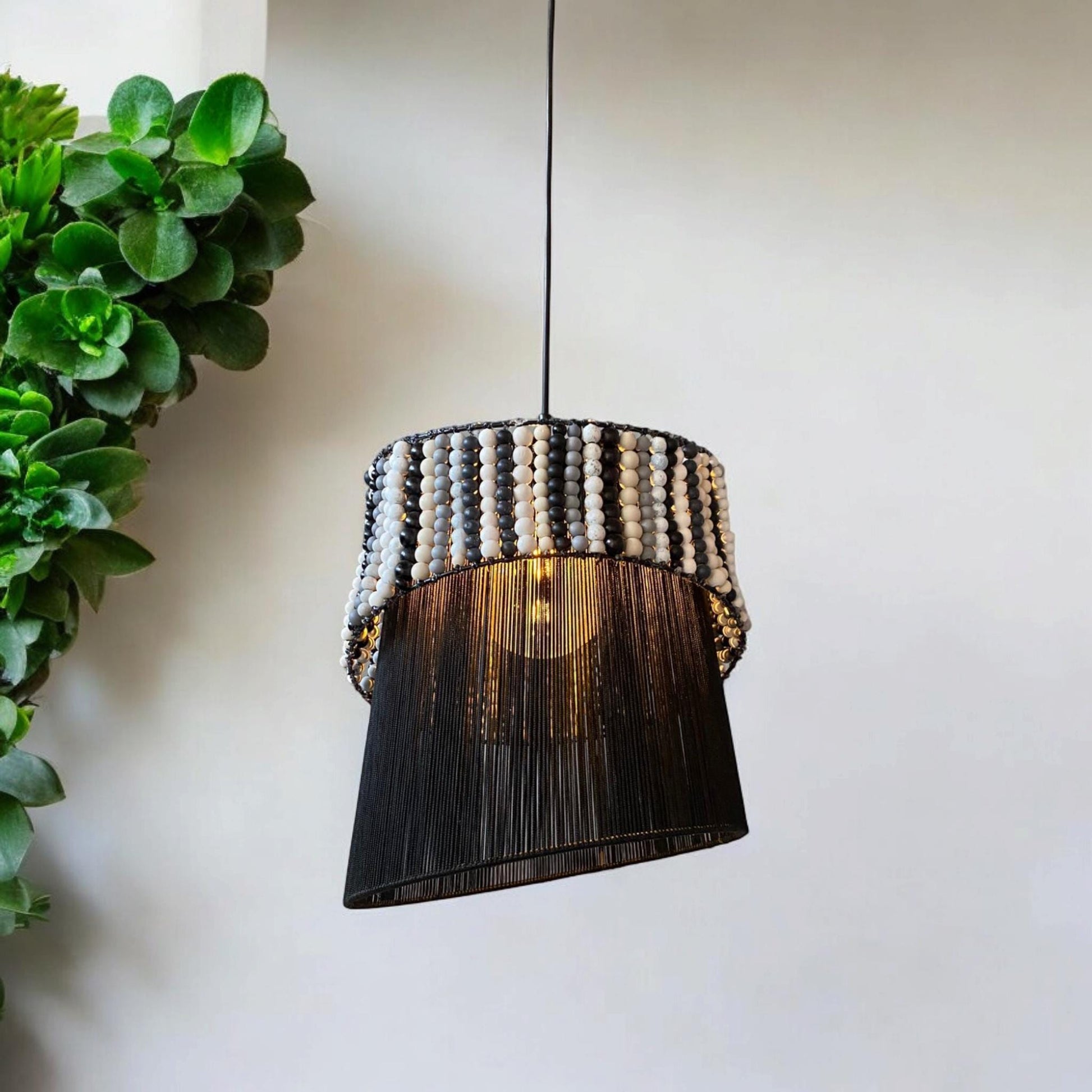 This unique asymmetrical chandelier blends black and white beads for a modern, minimalist style. Handcrafted with painted wooden beads and a polyester-wrapped base, it adds artistic elegance to any space with its 30 cm diameter and 40 cm height."